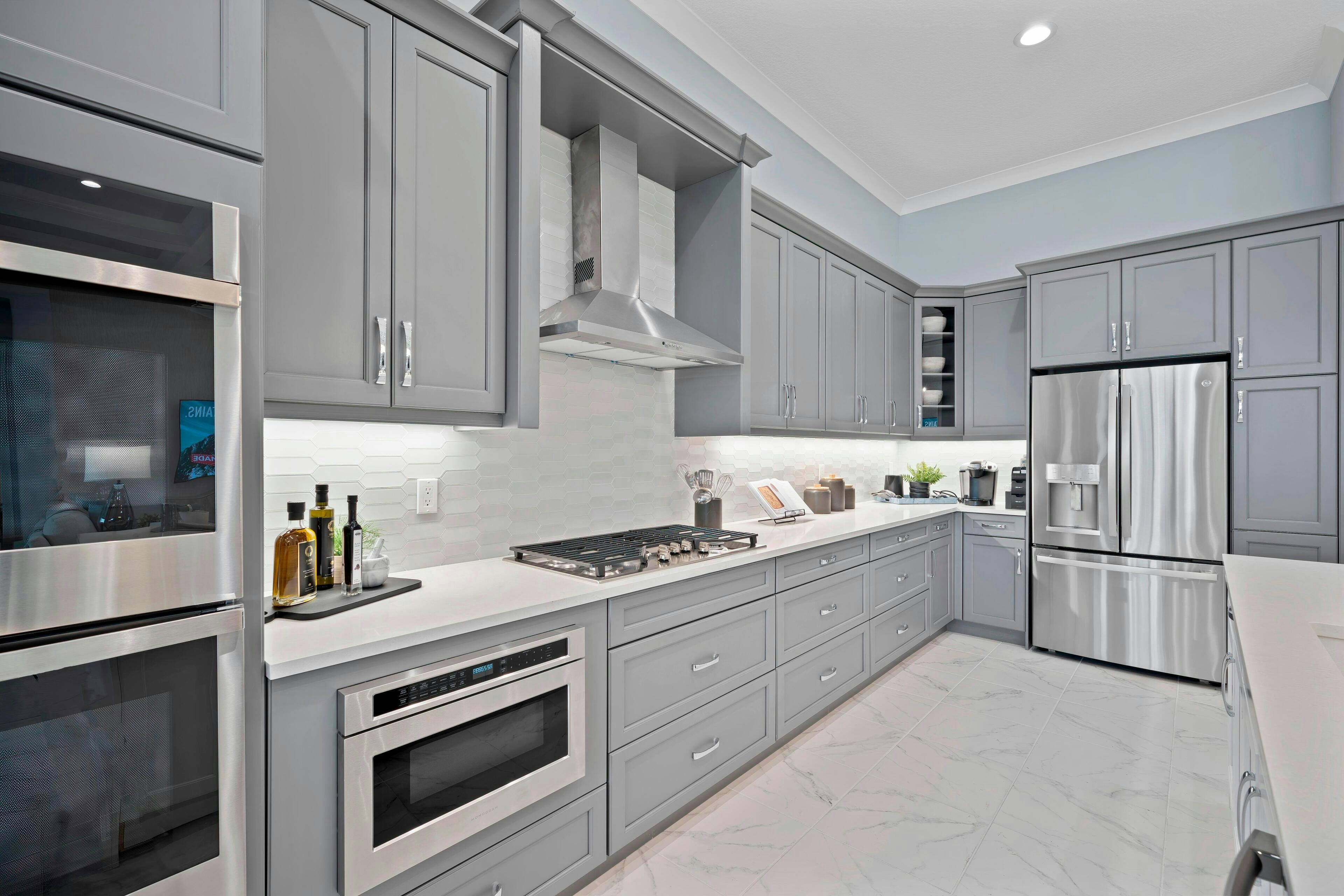 Cook wall in kitchen with grey cabinets, grey tile backsplash and stainless steel appliances