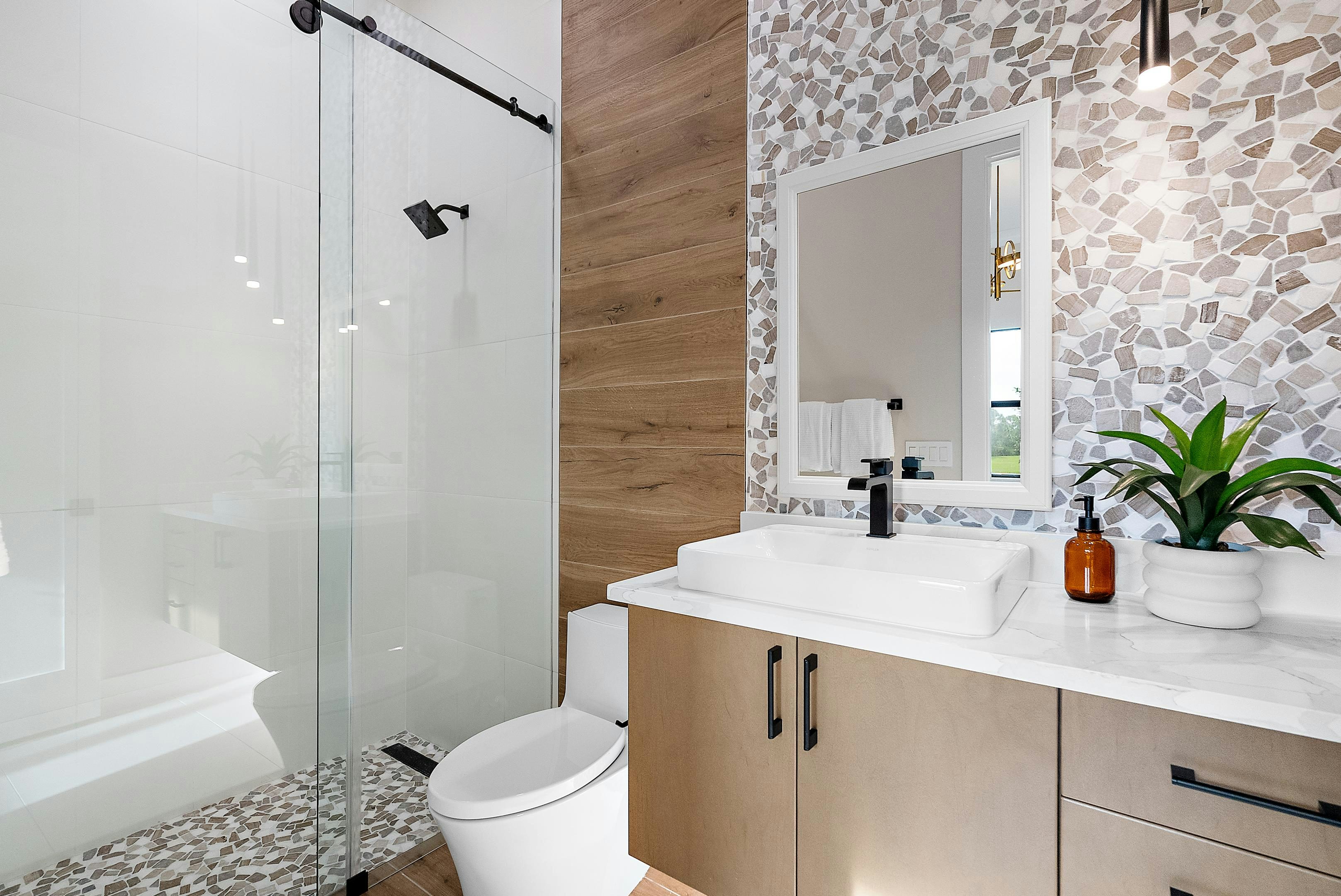 Secondary bath with pebble tile on floor and wall, black accents