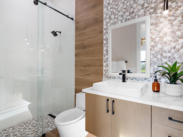 Secondary Bath | Keenan Model Secondary bath with pebble tile on floor and wall, black accents